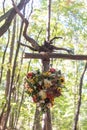 Vertical closeup shot of a flower bouquet in the shape of a heart hanged on the wooden logs outside