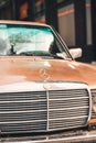 Vertical closeup shot of a front part of an old Mercedes Benz on the street.