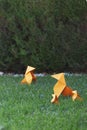 Vertical closeup shot of a group of orange origami figures on the grass