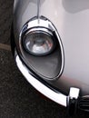 Vertical closeup shot of the headlight of a gray car