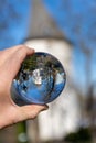 Closeup shot of a human hand holding a crystal ball with the reflections of a historic chapel