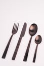 Vertical closeup shot of a knife, fork, and two spoons isolated on a light-colored background Royalty Free Stock Photo