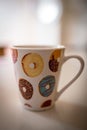 Vertical closeup shot of a mug with a picture of colorful and delicious round donuts