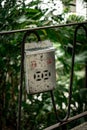 Vertical closeup shot of an old metallic post box on railing in Hong Kong park with blur background Royalty Free Stock Photo