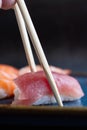 Vertical closeup shot of a pair of chopsticks picking delicious sashimi