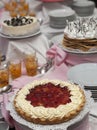 Vertical closeup shot of a pie with white cream and strawberries on the table with other desserts Royalty Free Stock Photo