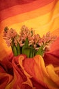 Vertical closeup shot of pink hyacinth flowers covered by red and yellow textile Royalty Free Stock Photo