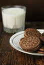 Vertical closeup shot of a plate of chocolate filled Oreos and a glass of milk in the background Royalty Free Stock Photo