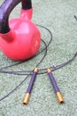 Vertical closeup shot of professional jump rope and a red round heavy weight on artificial grass