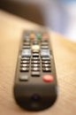 Vertical closeup shot of a remote controller on a wooden surface with a blurred background Royalty Free Stock Photo