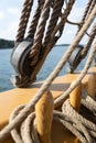 Vertical closeup shot of the ropes, the cable and the pulleys on a wooden sailing boat on the sea Royalty Free Stock Photo