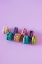 Vertical closeup shot of rows of colorful macarons on a pink background