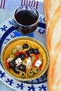 Vertical closeup shot of a salad with olives and feta next to a baguette and a glass of wine Royalty Free Stock Photo