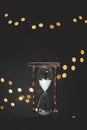 Vertical closeup shot of a sand glass timer with burred lights in the background Royalty Free Stock Photo