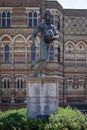 Vertical closeup shot of the sculpture of William Webb Ellis in front of a building on a sunny day