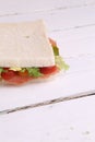 Vertical closeup shot of a serrano ham sandwich with tomatoes and lettuce on a white kitchen table Royalty Free Stock Photo