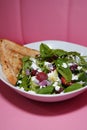 Vertical closeup shot of a spinach salad with toasted bread on the side in a white plate Royalty Free Stock Photo