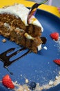 Vertical closeup shot of a spoon cutting a slice of carrot cake on a blue plate Royalty Free Stock Photo