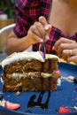 Vertical closeup shot of a spoon cutting a slice of carrot cake on a blue plate Royalty Free Stock Photo