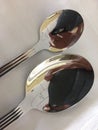 Vertical closeup shot of a teaspoon and a tablespoon on a white tablecloth