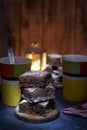 Vertical closeup shot of three brownie pieces stacked on each other with teacups in the background Royalty Free Stock Photo