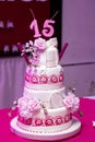 Vertical closeup shot of a three-layered 15th birthday cake with pink rose decorations Royalty Free Stock Photo