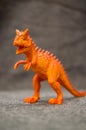 Vertical closeup shot of a toy figurine of an orange dinosaur