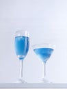 Vertical closeup shot of two glass of blue cocktails on white background. Royalty Free Stock Photo