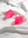 Vertical closeup shot of two vibrant pink hair rollers on a white cloth Royalty Free Stock Photo