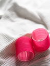 Vertical closeup shot of two vibrant pink hair rollers on a white cloth Royalty Free Stock Photo