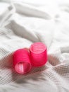 Vertical closeup shot of two vibrant pink hair rollers on a white cloth Royalty Free Stock Photo