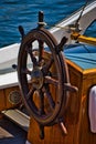 Vertical closeup shot of vintage wooden helm wheel on old boat on blue sea background on sunny day Royalty Free Stock Photo