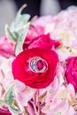 Vertical closeup shot of the wedding rings on the pink flower of the bride\'s bouquet Royalty Free Stock Photo