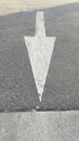 Vertical closeup shot of white arrow sign showing direction on an asphalt car park road Royalty Free Stock Photo