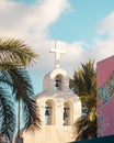 Vertical closeup shot of a white church spire with a cross near palm trees in Playa Del Car, Mexico Royalty Free Stock Photo