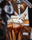 Vertical closeup shot of a white cream being poured on a glass of milkshake