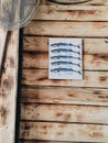 Vertical closeup shot of a white paper with fish hanged on the wooden wall of a fisherman house