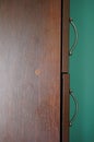 Vertical closeup shot of a wooden closet with two sections and a turquoise wall in the background