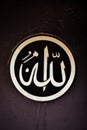 Vertical closeup shot of an "Allah" writing in Arabic in a circle on a metallic surface