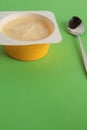 Vertical closeup shot of yogurt and a teaspoon on a green background
