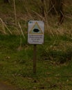 Vertical closeup of a sign, warning people about the dangerous wildlife in the area on a grass field Royalty Free Stock Photo