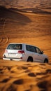 Vertical closeup of a silver Jeep driving on the sand in a yellow dessert on a sunny day