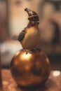 Vertical closeup of a small statue of a bird perched on a metal ball.