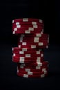 Vertical closeup of the stack of poker chips on black background.