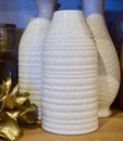 Vertical closeup of stacks of modern white vases on a wooden table