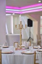 Vertical closeup of a table with dishes and gold candelabra with candles in wedding banqueting hall