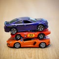 Vertical closeup of three Mattel Hot Wheels cars on top of each other.