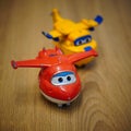 Vertical closeup of two Super Wings toy model planes on a wooden surface.