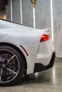 Vertical closeup of a white Toyota Supra A90 MKV end back led lights background showroom