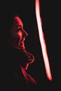 Vertical closeup of a woman smiling at red neon light